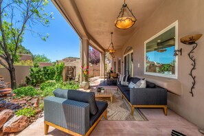 Un patio cubierto con mobiliario exterior, una fuente de agua y vistas del paisaje circundante.