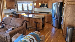 A kitchen with wooden cabinets, a stainless steel refrigerator, a microwave, and a large island with bar stools. - Vedauwoo, Curt Gowdy State Park, Cheyenne, and Laramie  close! (Cheyenne)