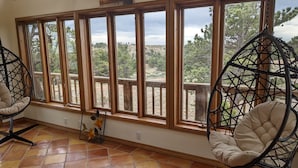 A room with large windows, a hanging chair, and a decorative plant. - Vedauwoo, Curt Gowdy State Park, Cheyenne, and Laramie  close! (Cheyenne)