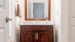 A bathroom with a wooden vanity, a mirror, and a towel rack.