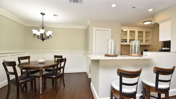 A dining area with a round table and chairs, a chandelier, and a kitchen with cabinets and a countertop. - CITY CONDO (Houston)