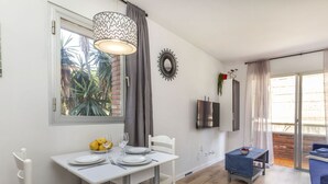 A dining area with a table set for two, a modern pendant light, and a view of the outdoors through a window. - Beautiful apartment for 4 guests with pool, A/C, WIFI, TV and balcony (Lloret De Mar)