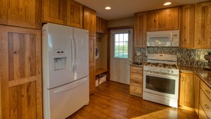 A kitchen with wooden cabinets, a refrigerator, a microwave, and a stove.