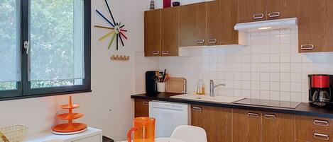 A modern kitchen with wooden cabinets, a white countertop, and a dining area set for four.