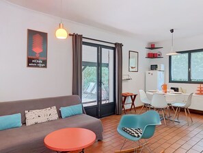 A modern living room with a sofa, a round table, and a dining area with chairs.
