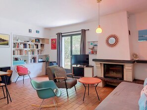Un salon avec une cheminée, un téléviseur, une bibliothèque et un coin repas.