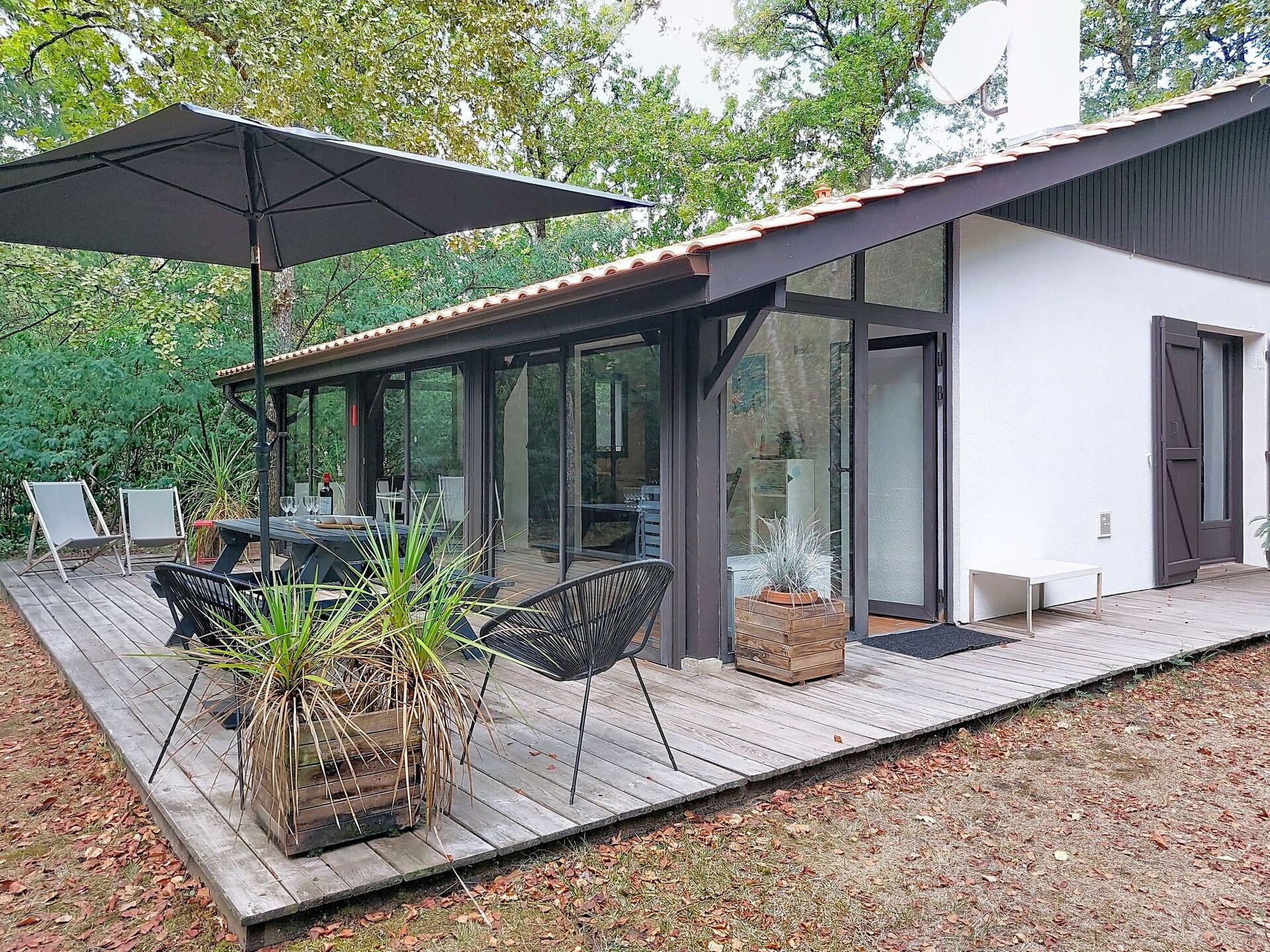 A modern outdoor deck with a dining area, a covered seating area, and a potted plant.