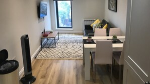 Ein modernes Wohnzimmer mit Essbereich, einem großen Fenster und einer Heizung.
