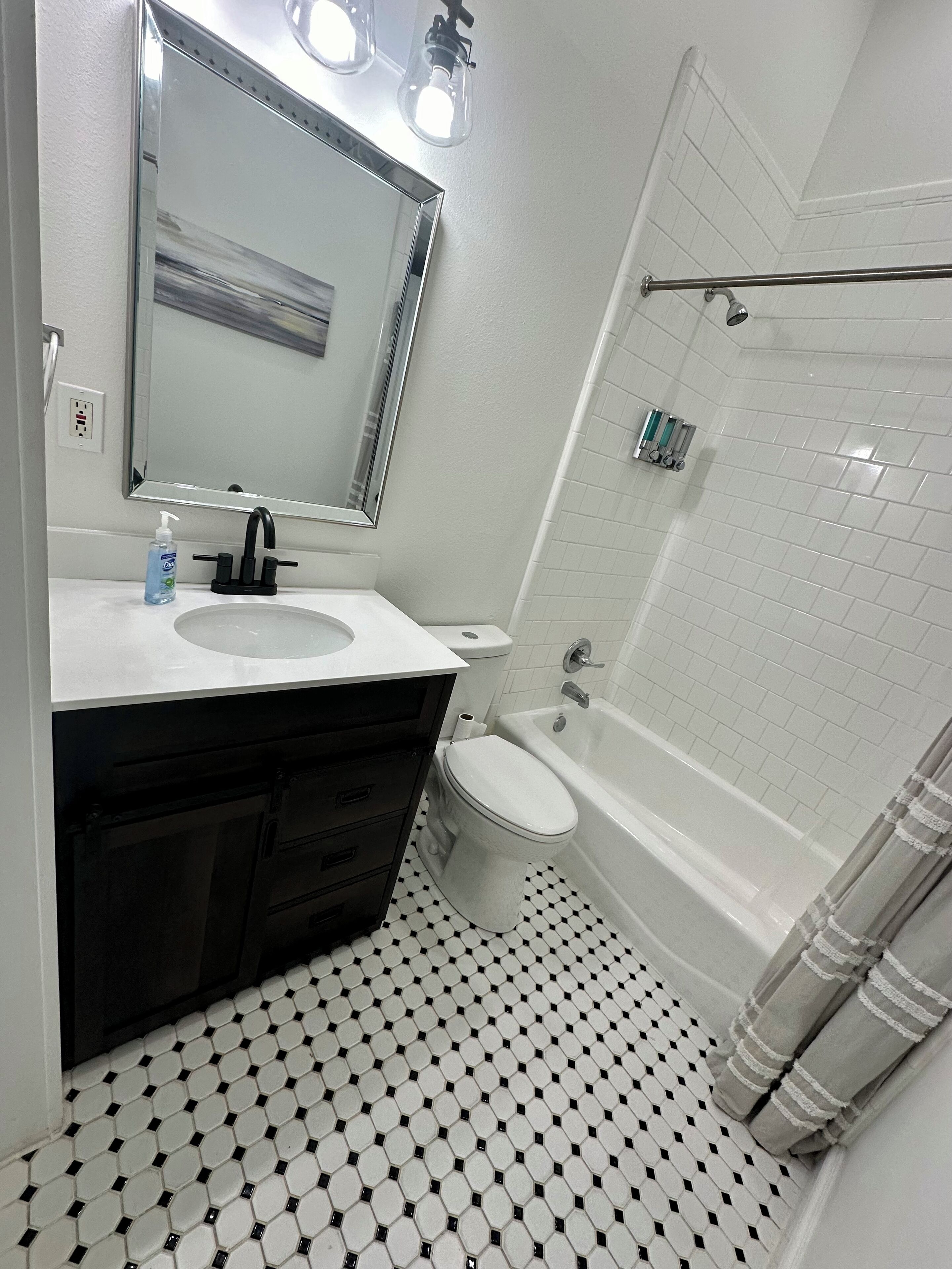 Une salle de bain avec un lavabo blanc, un meuble-lavabo noir, des toilettes et une baignoire.