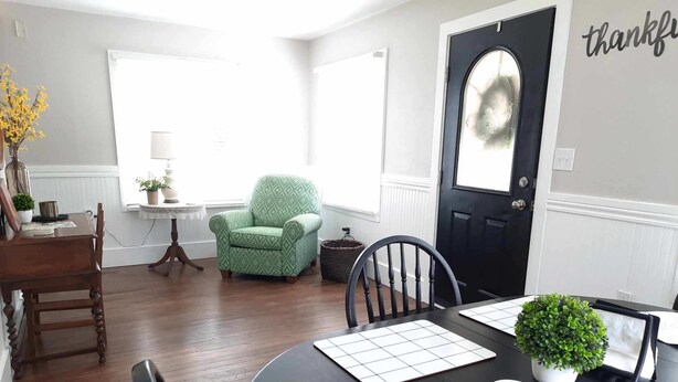 Un comedor con una mesa negra, individuales blancos y un sillón estampado en verde.