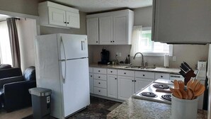 Una cocina moderna con armarios blancos, un refrigerador, una estufa y un cubo de basura.