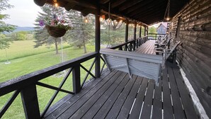A wooden deck with a railing, hanging flower baskets, and string lights.