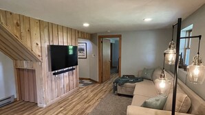 A modern living room with a wooden accent wall, a flat-screen TV, a sofa, and a coffee table.