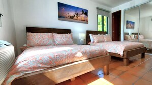Een slaapkamer met twee bedden, een groot raam en uitzicht op het strand.