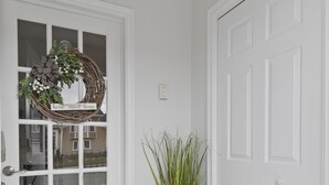 A clean, white entryway with a glass door, a potted plant, and a dark gray doormat. - *WOW!!* Executive cozy home with 3 beds, work station & gym (St. John's)