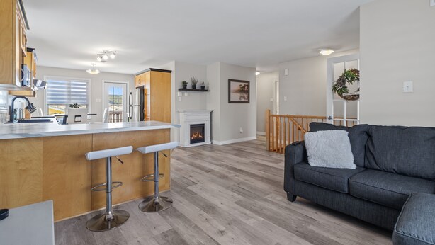 A modern kitchen with a bar area, a fireplace, and a living room with a sofa. - *WOW!!* Executive cozy home with 3 beds, work station & gym (St. John's)