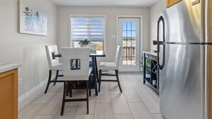 A modern kitchen with a stainless steel refrigerator, a dining table with chairs, and a window with blinds. - *WOW!!* Executive cozy home with 3 beds, work station & gym (St. John's)