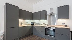 Een moderne keuken met grijze kastjes, een inbouwoven en een magnetron.