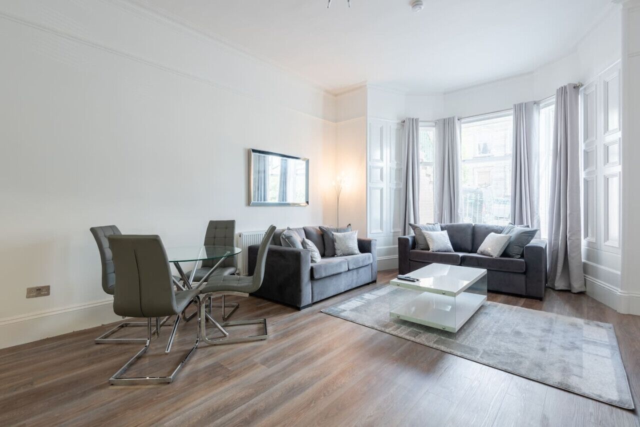 A modern living room with a glass coffee table, two sofas, and a dining table with chairs.