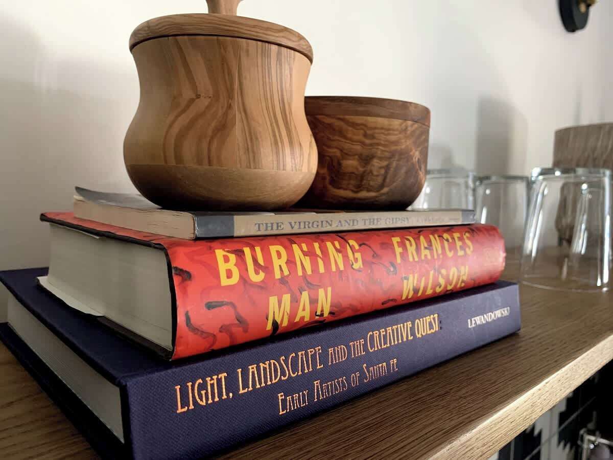 A stack of books on a shelf, including titles like "Burning Frances Man" and "Light, Landscape and the Creative Quest."