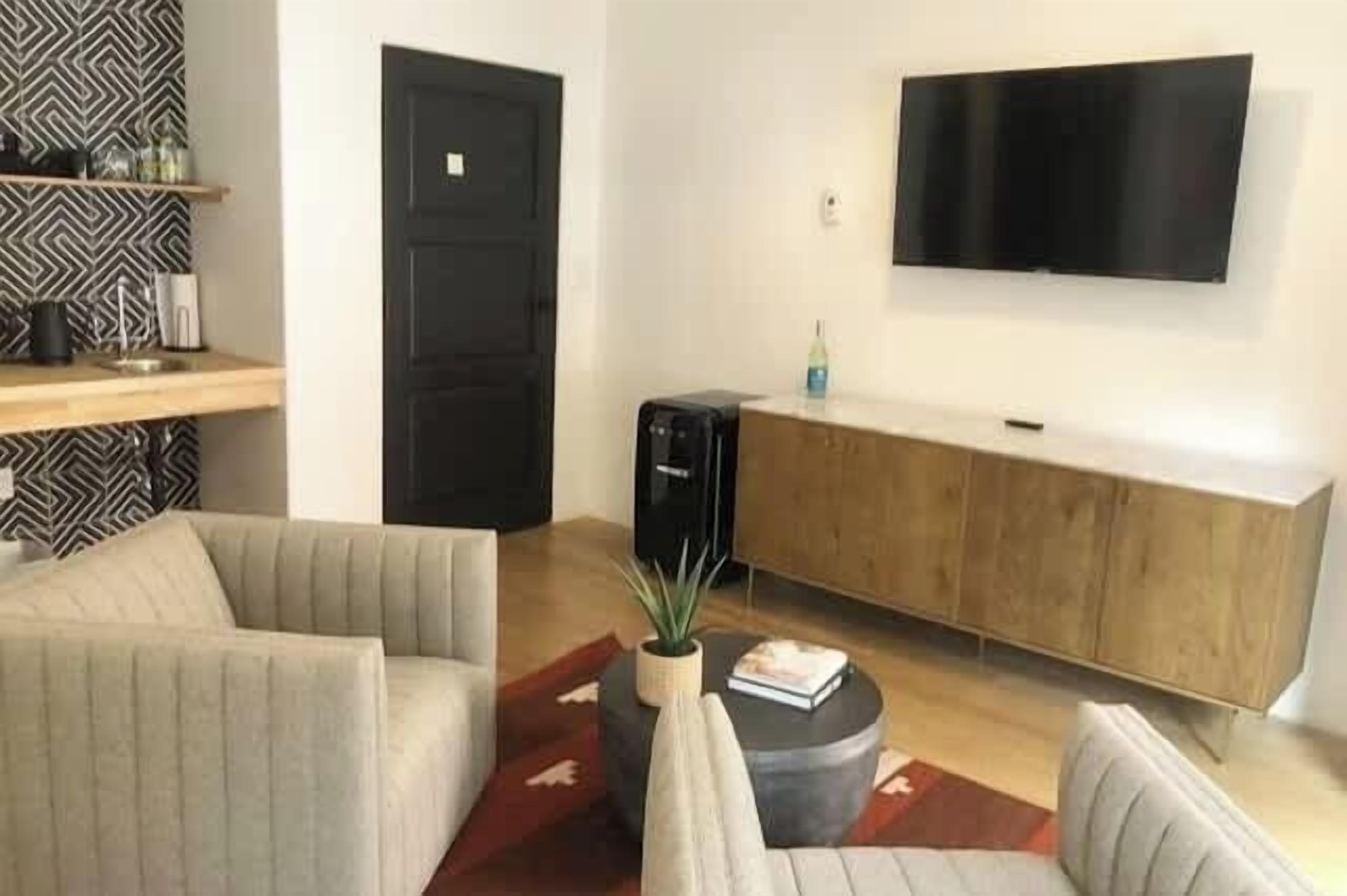 Ein modernes Wohnzimmer mit einer Couch, einem Couchtisch, einem an der Wand montierten Fernseher und einem Holzkabinett.