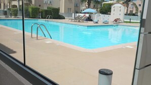 En pool med fri sikt över poolområdet, inklusive solstolar och ett litet parasoll.