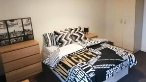 Ein Schlafzimmer mit Bett, Schminktisch, Nachttisch, Lampe und Kleiderschrank.