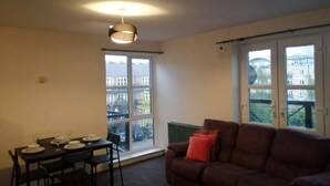 Ein Wohnzimmer mit Essbereich, einem braunen Sofa und einem Tisch für vier Personen.