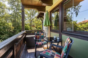 A wooden deck with two plaid chairs and a small table, overlooking a forested area. - Studio Bergblick with Mountain View, Balcony & Wi-Fi (Inzell)