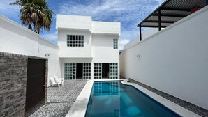 A modern building with a swimming pool, white walls, and a stone facade. - Magnífica casa con piscina privada a 10 min del mar (Cancún)