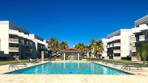 Zona de piscina con un pabellón, palmeras y edificios modernos.