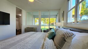 Un dormitorio con una cama grande, un televisor de pantalla plana y vistas al exterior a través de una puerta corrediza de vidrio.