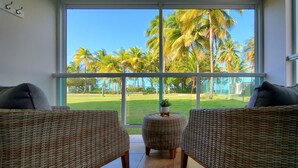 Una habitación con muebles de mimbre, un ventanal y vistas a palmeras.