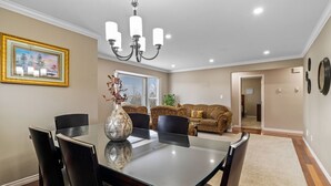 A dining area with a glass table, black chairs, and a vase. There is a chandelier above and a framed picture on the wall. - Beautiful Home in Langley with Huge Patio (Langley)