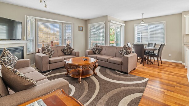 A spacious living room with a large sectional sofa, a coffee table, and a dining area with a table and chairs. - Beautiful Home in Langley with Huge Patio (Langley)