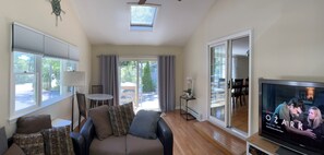 A living room with a sofa, TV, and a view of the outdoors.