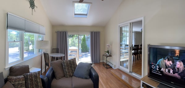 A living room with a sofa, TV, and a view of the outdoors.