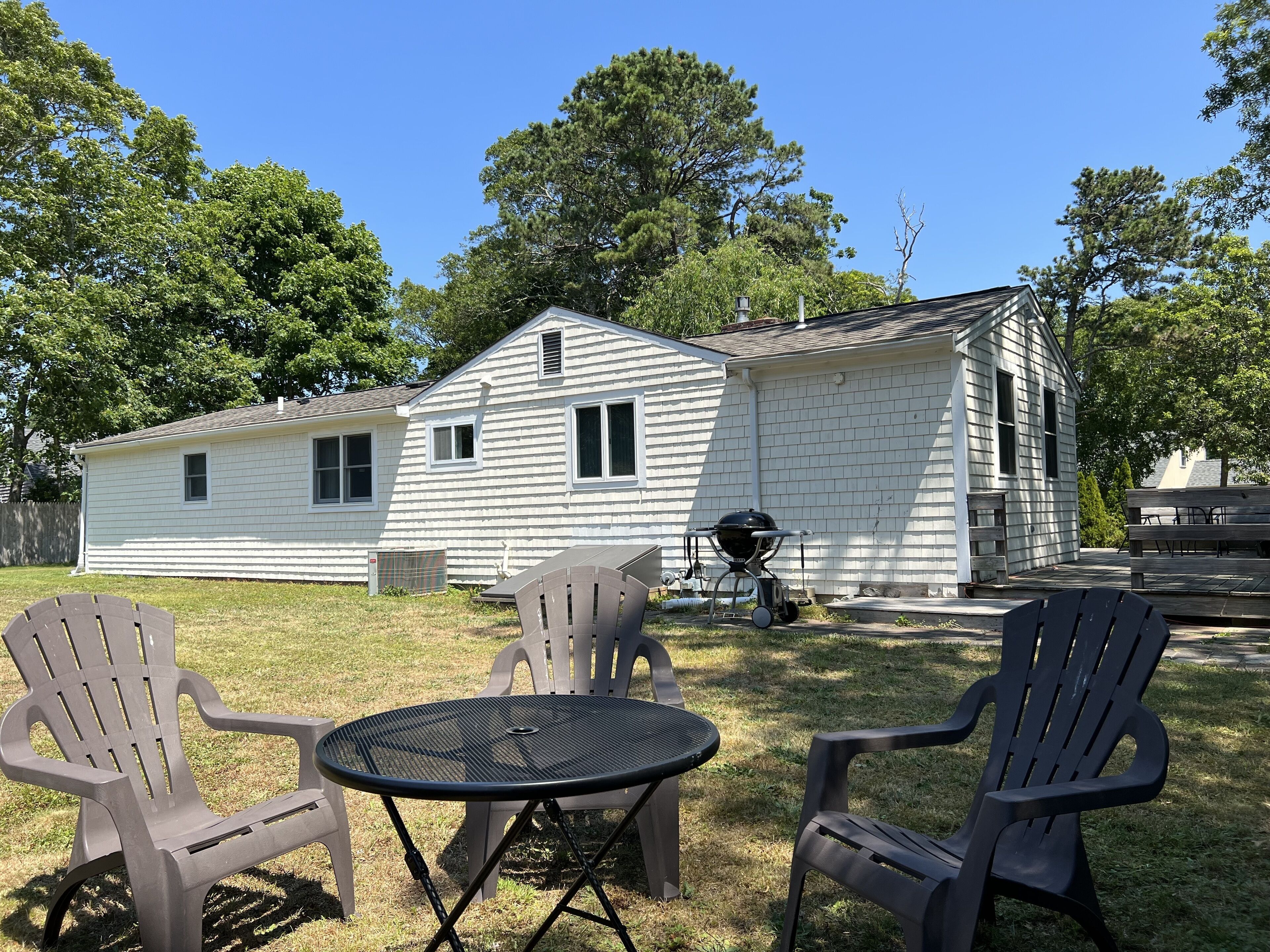 A single-story house with a white exterior, a front porch, and a grill.