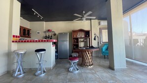 Una cocina compacta con refrigerador, una mesa de comedor y taburetes de bar.