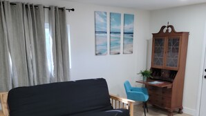 Ein Wohnzimmer mit einem Holzsofa, einem blauen Sessel, einem Holzkabinett und einem Bild an der Wand.