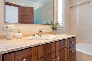 Une salle de bain avec un lavabo, un miroir, des meubles en bois et un espace douche.