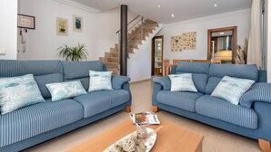 A living room with two blue striped sofas, a wooden coffee table, and a staircase leading to another room.