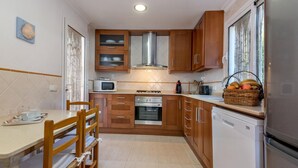 A compact kitchen with wooden cabinets, a microwave, a stove, and a refrigerator.