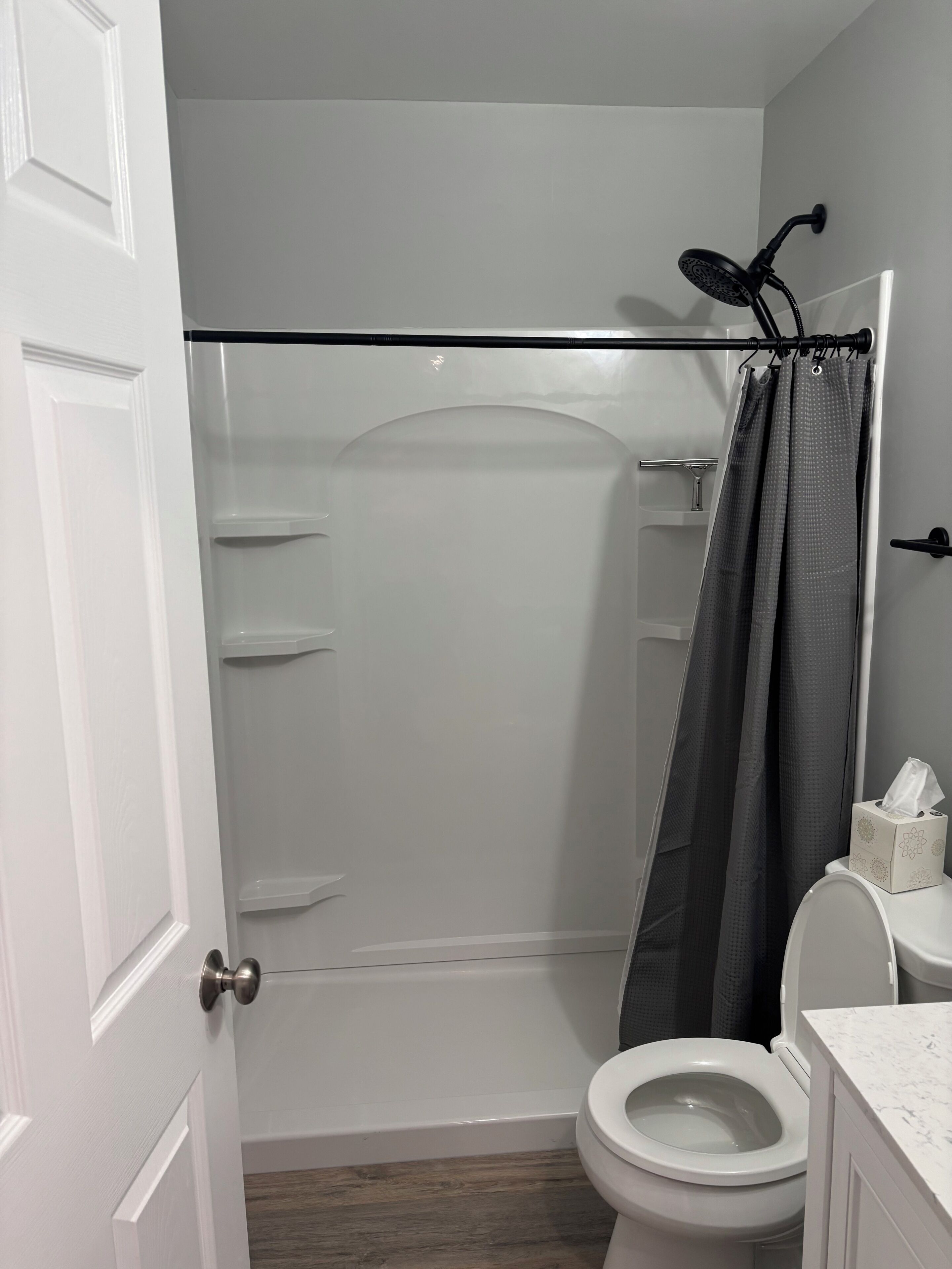 Un baño con ducha, inodoro y un perchero para toallas.