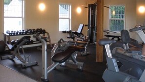 Ein Fitnessstudio mit verschiedenen Trainingsgeräten, darunter Laufbänder, Kurzhanteln und Kraftgeräte.