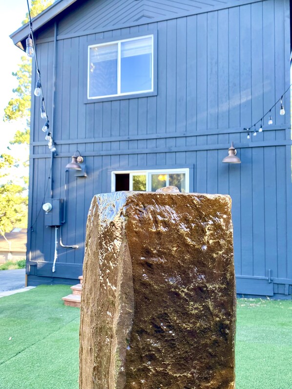 A large rock in a yard with a blue house in the background. - Bass Lake Escape-Near the Shore • Explore Yosemite • Close to the Pines Village (Bass Lake)