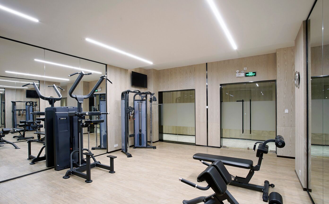 Un gimnasio moderno con diversas máquinas de ejercicio, una banca y un espejo.
