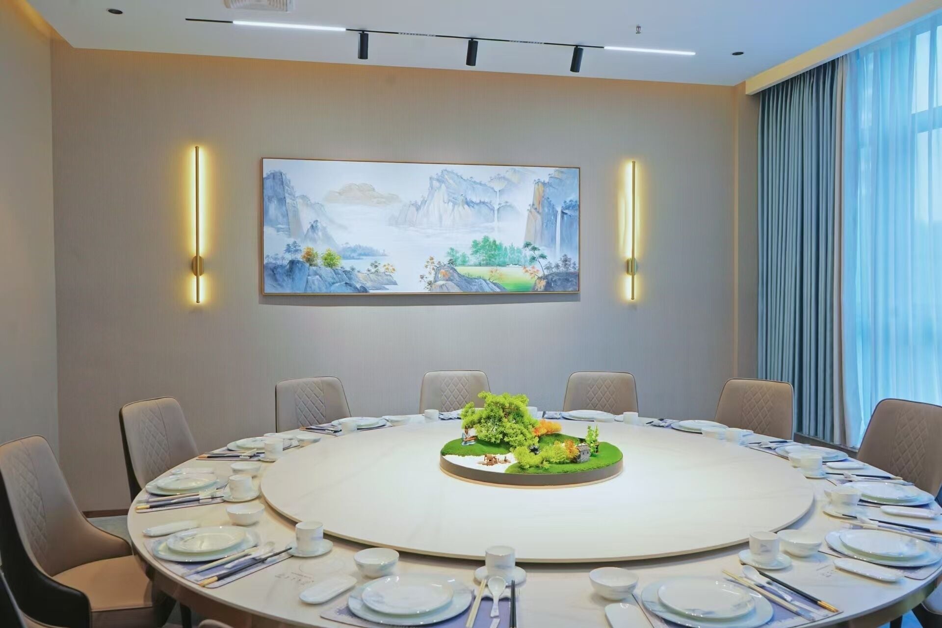 Une salle de conférence avec une table ronde, des chaises et un tableau accroché au mur.