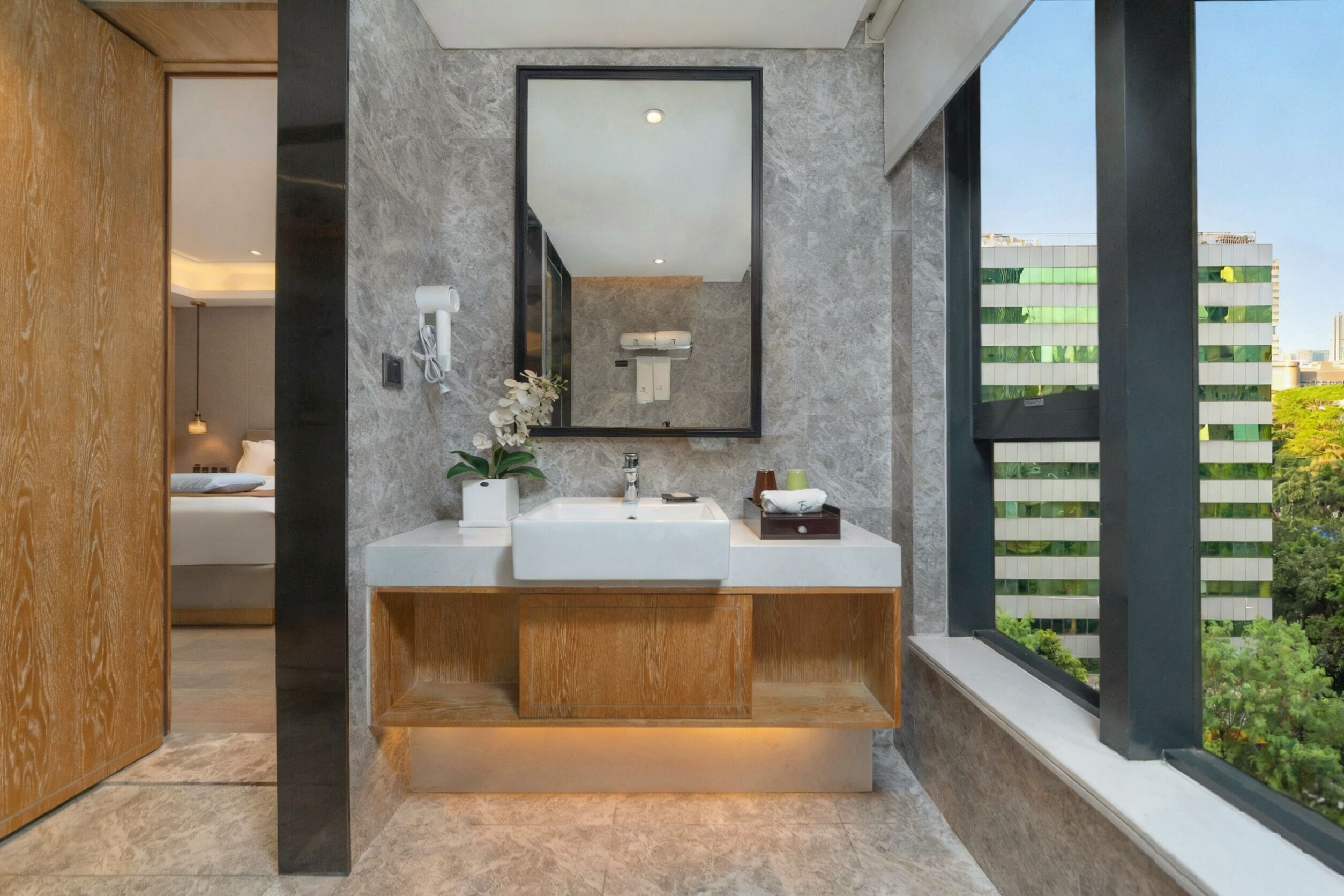 A modern bathroom with a dual sink vanity, a large mirror, and a view of a cityscape through a window.