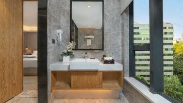A modern bathroom with a dual sink vanity, a large mirror, and a view of a cityscape through a window.